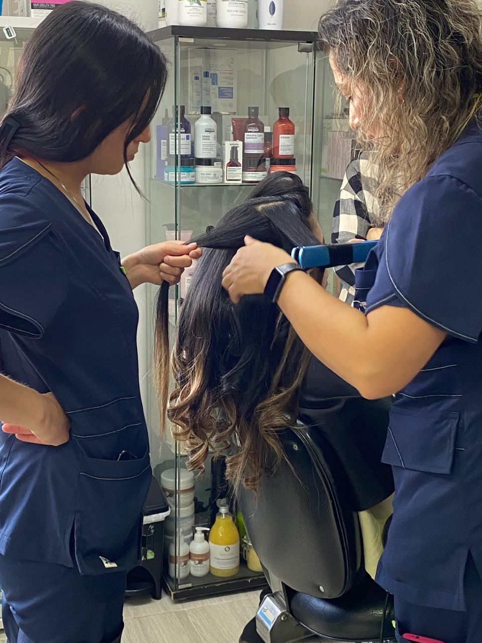 Dos estilistas trabajando el cabello de una clienta
